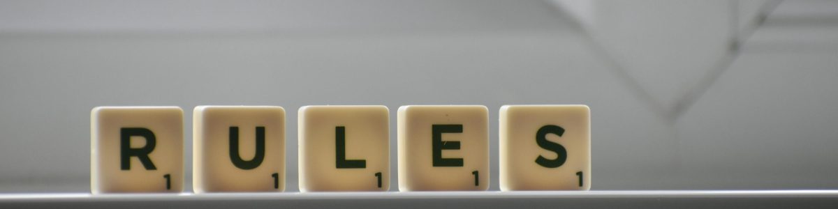 Identical small square shaped cubes with RULES title and numbers on white windowsill near window in house in daylight